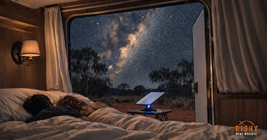 Cosy caravan bed with Starlink Mini dish glowing outside under Milky Way outback night sky