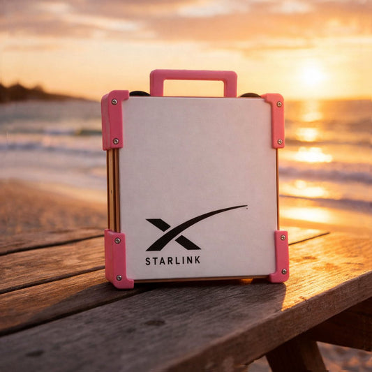 Pink Starlink Mini Magnetic Mount on timber table at Australian beach sunset - portable satellite dish carry frame by Dishy Mini Mounts